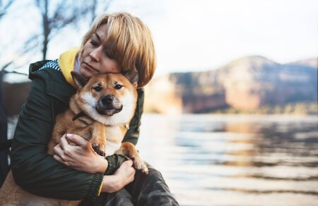 tourist traveler girl together dog on background mountain lake, happy woman hug puppy pet nature, friendship love conceptの写真素材