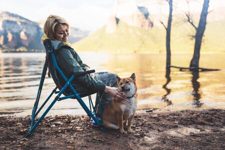 tourist traveler girl together dog on background mountain lake, happy fun woman hugging puppy pet nature, friendship love conceptの写真素材