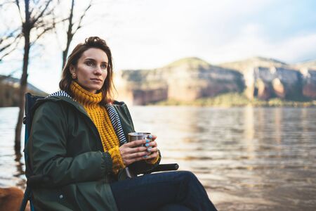 tourist traveler girl relax drink tea on background mountain,  woman rest on lake shore nature trip, vacation conceptの写真素材