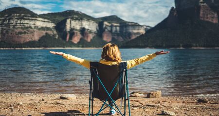 happy tourist traveler with raised hands, hiker enjoying mountains lake with arms outstretched breathing of fresh clean air in trip in spain, relax holidayの写真素材