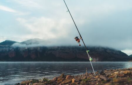 fishery concept, fishing rod, hobby sport on mist lake, catch fish on river on background foggy...