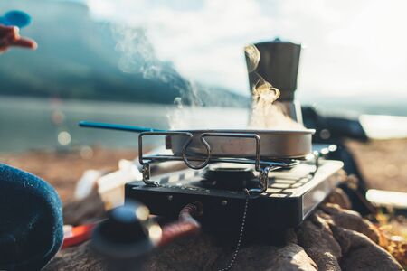 camping cooking in nature outdoor, prepare breakfast picnic in mist morning; cooker food metal gas stove on stone; tourism recreation outside; campsite lifestyleの写真素材