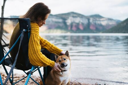 tourist traveler girl relax tender together friends dog on background mountain scape,  woman hugging pet rest on lake shore nature tripの写真素材