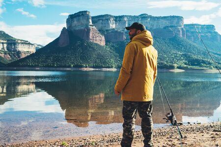 fisherman hold fishing rod, man enjoy hobby sport on lake, person catch fish on river on background mount, fishery concept の写真素材