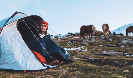 girl relax in campsite, tourist in camp tent  trip on mountain nature, hiker woman enjoys wild horses on valley tripの写真素材