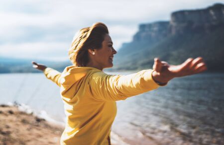smile tourist traveler standing with raised hands, girl hiker enjoying mountains lake arms outstretched breathing of fresh clean air in trip in spain, relax holidayの写真素材