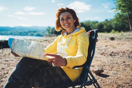 traveler smile girl looking on map vacation trip, woman planning trip, hipster tourist on background nature, enjoy lifestyle holiday conceptの写真素材