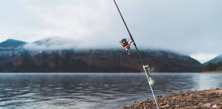 fishery concept, fishing rod, hobby on mist lake, catch fish on river on background foggy mount, holiday relaxation vacationの写真素材