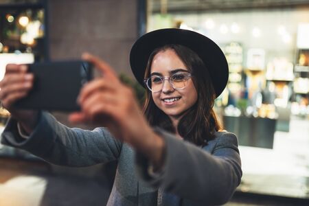 Smile girl take selfie outdoors using mobile smartphone on background bokeh light in night city, womn hold in hands sellphone, online  internetの写真素材