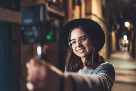 Traveler female blogger shooting video for vlog social media with digital camera. Happy woman vlogger taking photo selfieの写真素材
