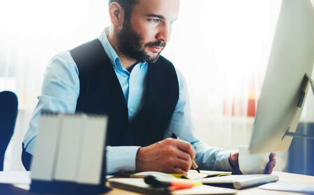 Manager writes in notebook at home workplace. Bearded businessman working at office. Consultant thinking looking in monitor computer, online internet work process concept, social distance, student study online educationの写真素材