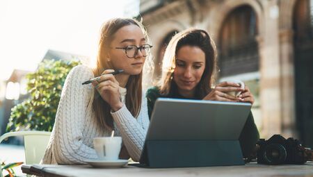 Girls drink coffee relax in cafe outdoor in europe city. Freelancer communicate on project, woman shopping online. Working business processの写真素材