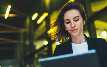 portrait professional female manager looking on screen tablet standing near office in evening...