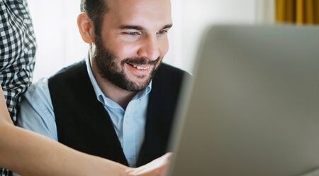 Bearded young businessman working at office. Director man thinking looking in monitor computer. Managers meeting. Idea, alalyze marketing plans. Workplace teamwork conceptの写真素材