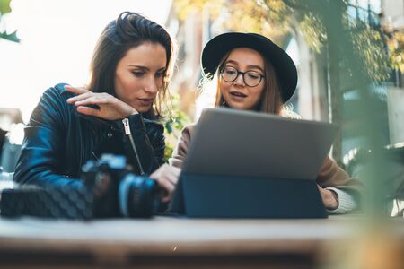 Freelancer communicate on project, girls shopping online on wifi tablet in cafe outdoor. Students studies on internet. Working business processの写真素材