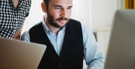 Bearded young businessman working at office. colleague discuss startup project, director looking in monitor computer. Managers meeting marketing plans. Workplace teamwork conceptの写真素材