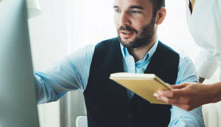 Bearded young businessman working at office. Director man thinking looking in monitor computer. Managers meeting. Idea, alalyze marketing plans. Workplace teamwork concept, Smiling colleague designer consultant discuss startup projectの写真素材