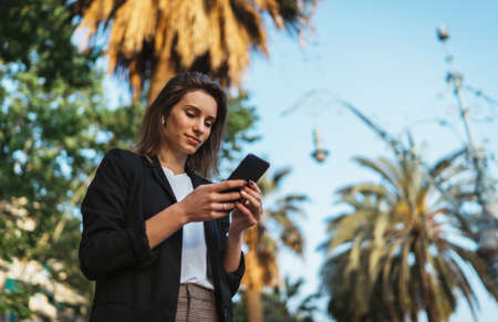 successful business woman wearing suit using modern smartphone to go before going to work early in...