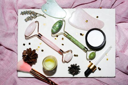 Green and pink face roller on white background. Face massagers good for skin.