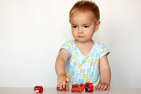 Cute toddler boy playing with wooden toy cars and imagining an accident on white background, safety and traffic regulationsの写真素材