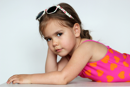 Cute baby girl wearing swimming suit and sun glasses over white background, summer vacation conceptの写真素材