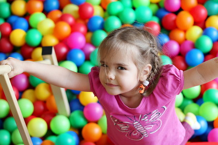 Happy girl playing and having fun at kindergarten with colorful balls, family weekend concept, happy birthday and merry partyの写真素材