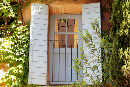 Typical wooden window with green ivy in a village in La Provence, wooden windows with plants, beautiful view, outdoorsの写真素材