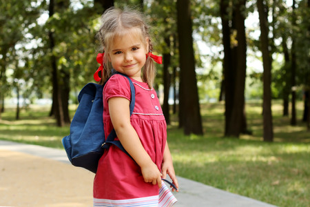 Beautiful little girl with backpack walking in the park ready back to school, fall outdoors, education conceptの写真素材