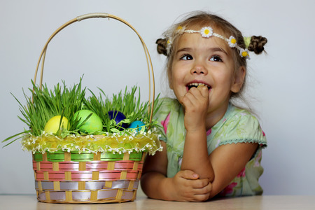 Little smiling girl with Easter basket with eggs decorated with the grass after egg hunt, happy family holidayの写真素材
