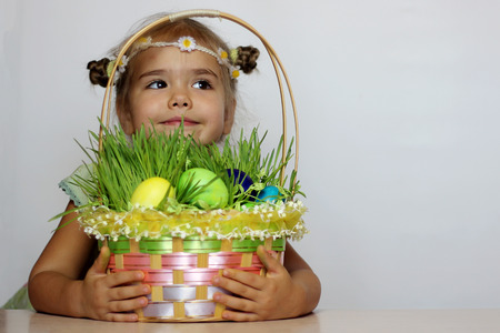 Little smiling girl Easter basket with eggs decorated with the grass after egg hunt, happy family holidayの写真素材