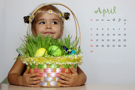 April 2017 calendar with smiling girl with Easter basket with eggs decorated with the grass after egg huntの写真素材