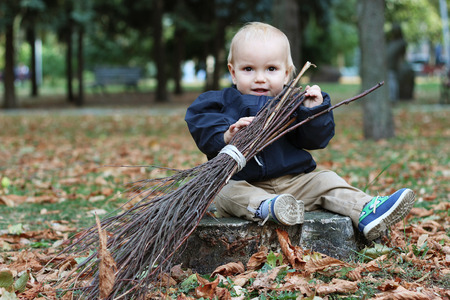 Cute baby boy holding a broom in the city parkの写真素材