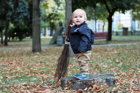 Cute baby boy holding a broom in the city parkの写真素材