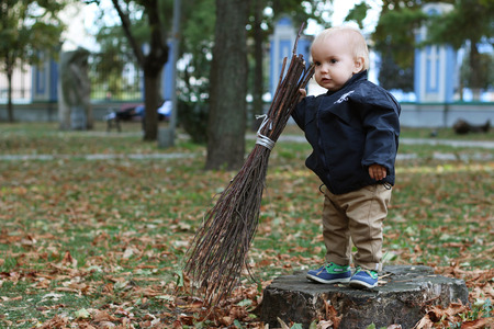 Cute baby boy holding a broom in the city parkの写真素材