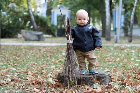Cute baby boy holding a broom in the city parkの写真素材