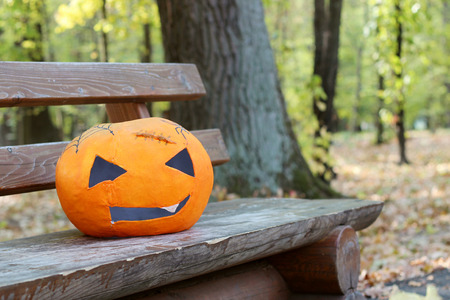 Pumpkin papier-mache mask laying on a wooden bench in the autumn parkの写真素材