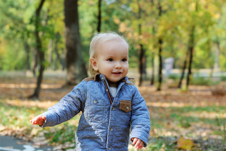 Handsome toddler running forward along the road in the autumn parkの写真素材