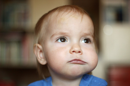 Cute blond baby boy with puffed-out cheek because of sugar candy, indoor portraitの写真素材