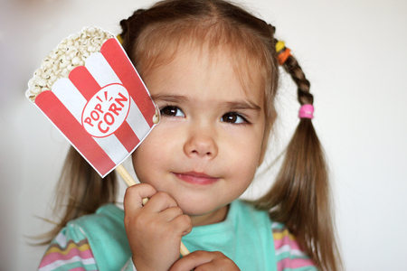 Dreaming pretty toddler girl with popcorn paper decoration, indoor portraitの写真素材