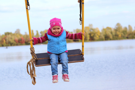 Smiling toddler flying on a swing against blue skyの写真素材