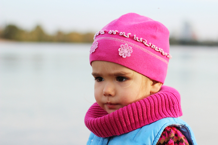 Serious toddler on the autumn beach against blue skyの写真素材