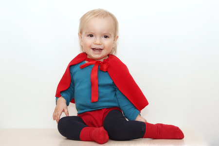 Funny toddler (boy) dressed as a superhero over white background, indoor portrait, superhero conceptの写真素材