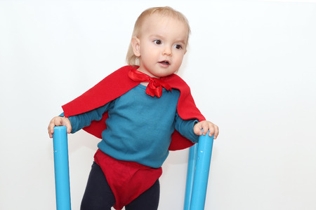 Funny toddler (boy) dressed as a superhero over white background, indoor portrait, superhero conceptの写真素材