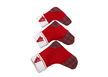 Three red Christmas socks with tree decor for Santa gifts arranged like an upward arrow or a New Year Tree on white background, winter holidays symbolの写真素材