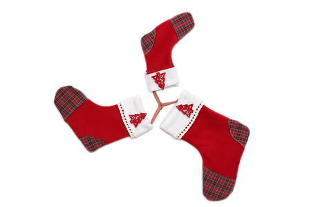 Three red Christmas socks with tree decor for Santa gifts arranged like a snowflake or a star on white background, winter holidays symbolの写真素材