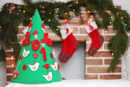 Handmade New Year tree with 2016 sign over soft blurred Christmas decorated fireplace with three different size Santa socks, winter holiday conceptの写真素材