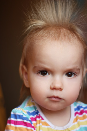 Surprised cute child (boy) with fun face and hair stood on end, indoor portraitの写真素材