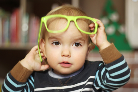 Funny kid boy with green eyeglasses, indoor portraitの写真素材