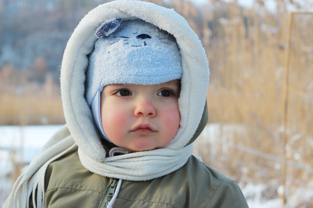 Little toddler boy having fun on the bank of the frozen lake at winter day, winter outdoorの写真素材