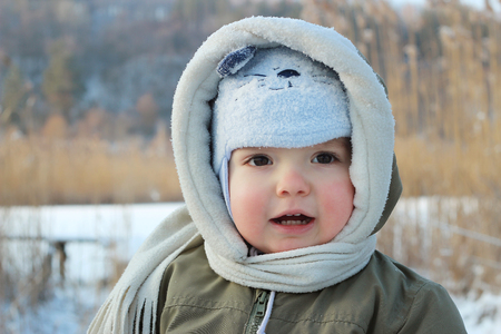 Little toddler boy having fun on the bank of the frozen lake at winter day, winter outdoorの写真素材